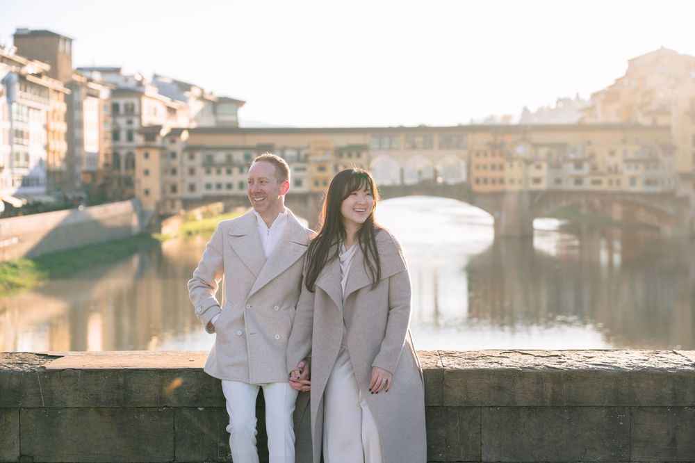 A romantic black and white photo series of a couple in light colored outfits sitting by a waterfront Florence Tuscany couples photographer.