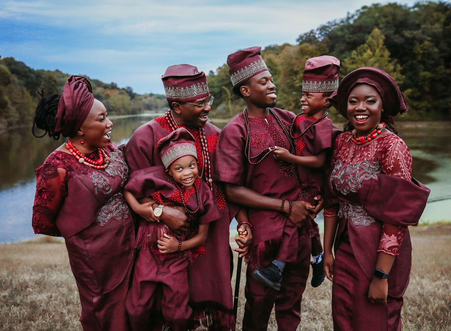 Group wearing coordinated burgundy graduation robes posing together outdoors.