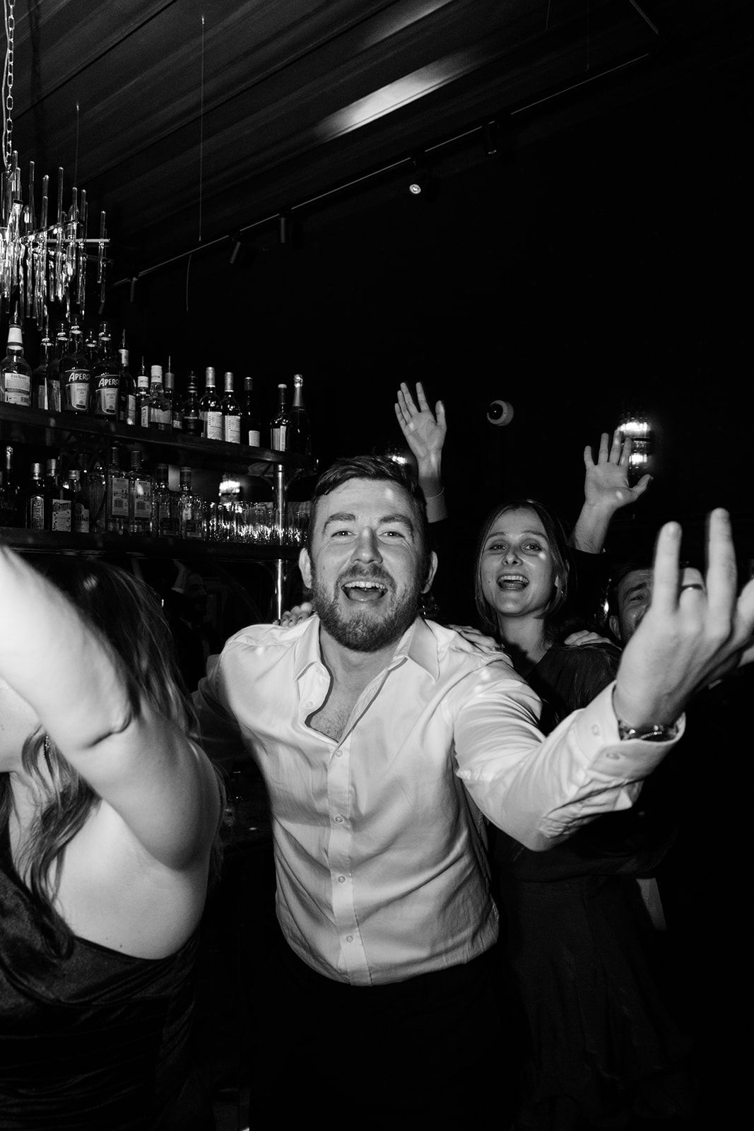 A black and white photo sequence shows people laughing and raising their hands at a bar.