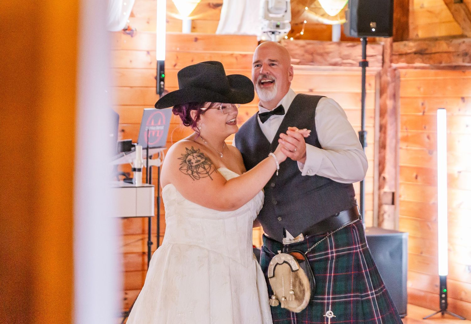 A joyful couple shares their first dance at a rustic barn wedding venue with exposed brick walls.