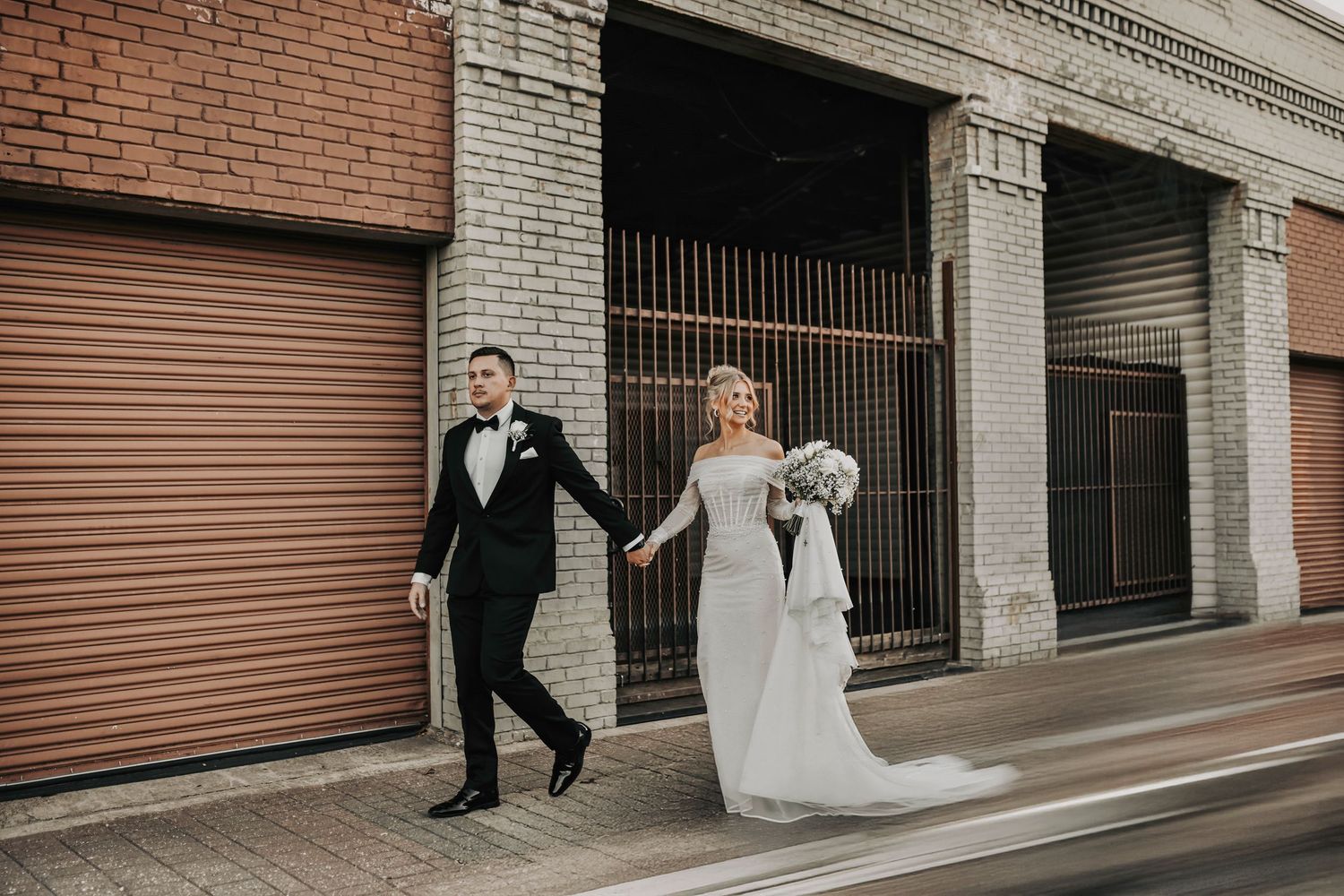 Bride and groom sharing candid editorial portraits in Deep Ellum at sunset with modern urban textures and artsy brick walls behind them