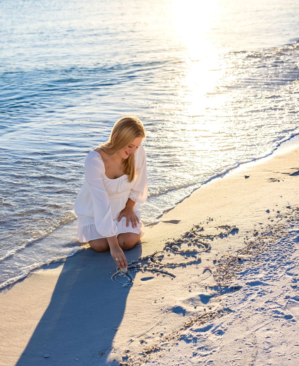A serene beach scene at sunset with gentle waves lapping at the sandy shore while a figure sits in contemplation.