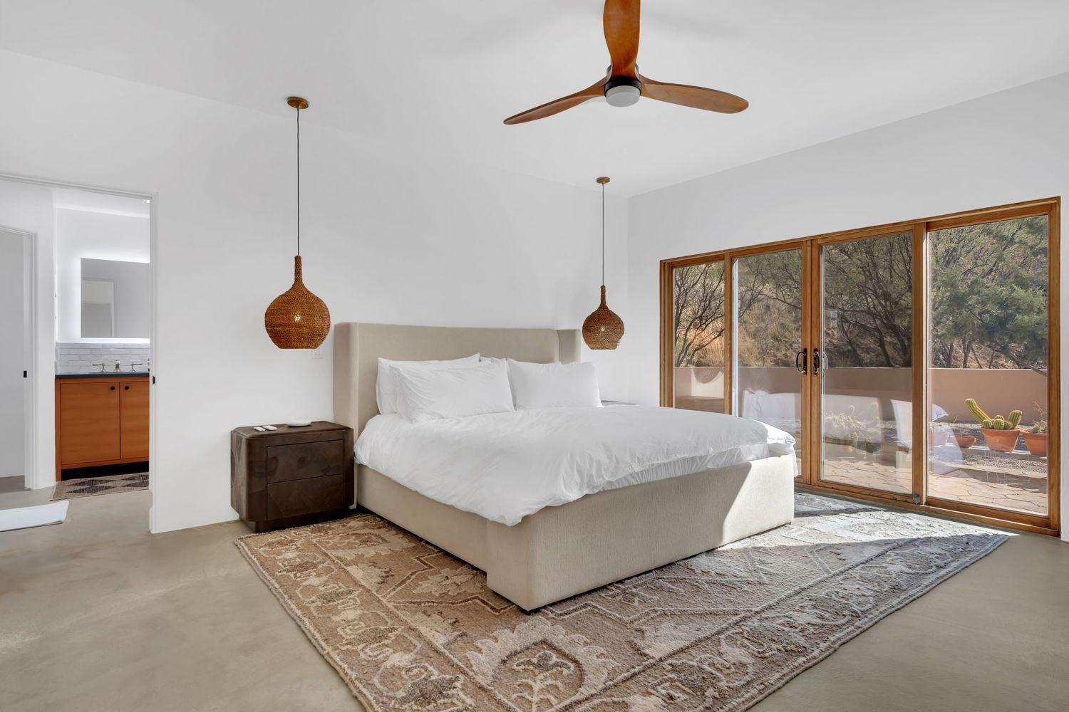 Spacious bedroom with wooden ceiling beams, large windows, and neutral decor.