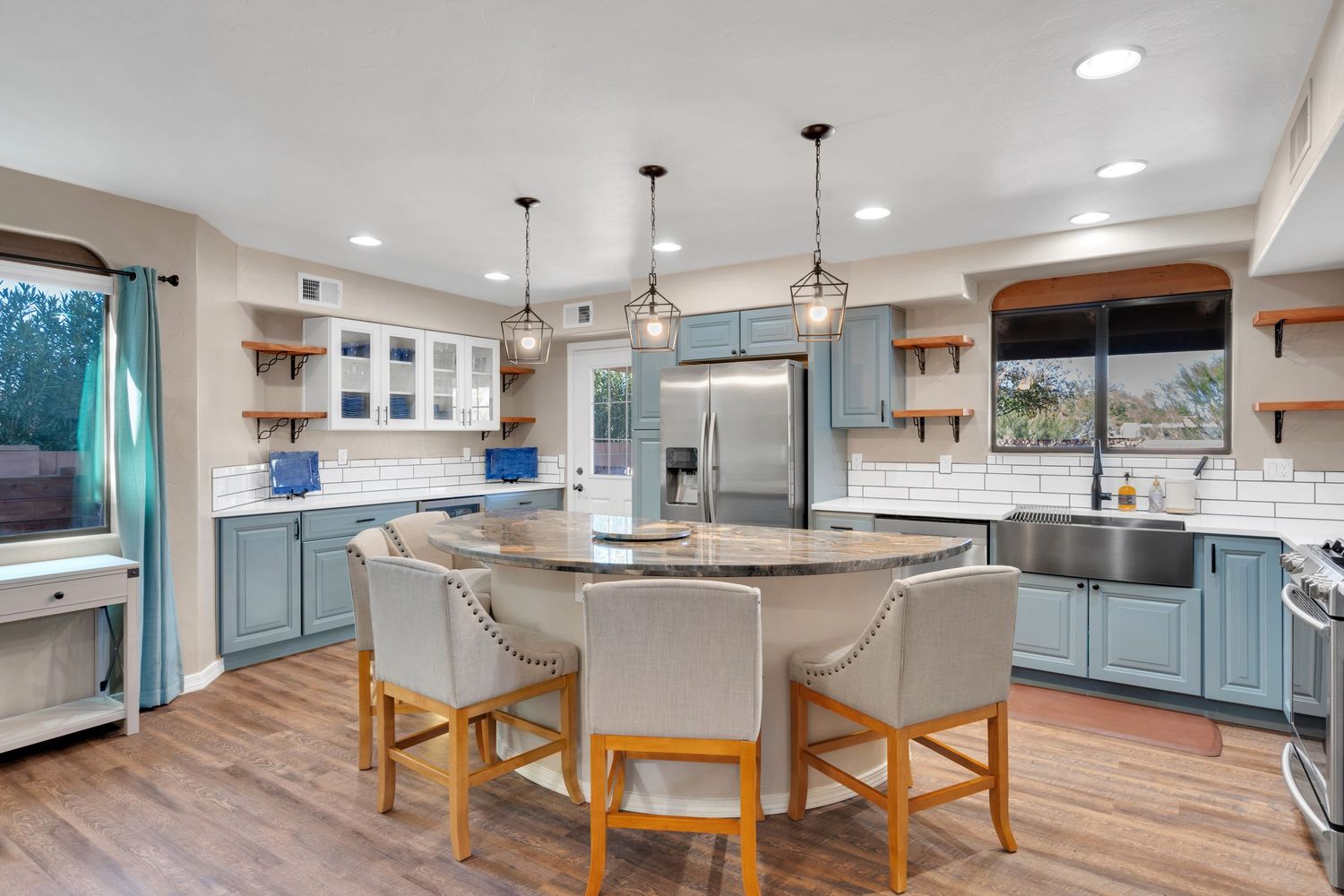 Modern kitchen interior with blue cabinets, pendant lights, and large center island.