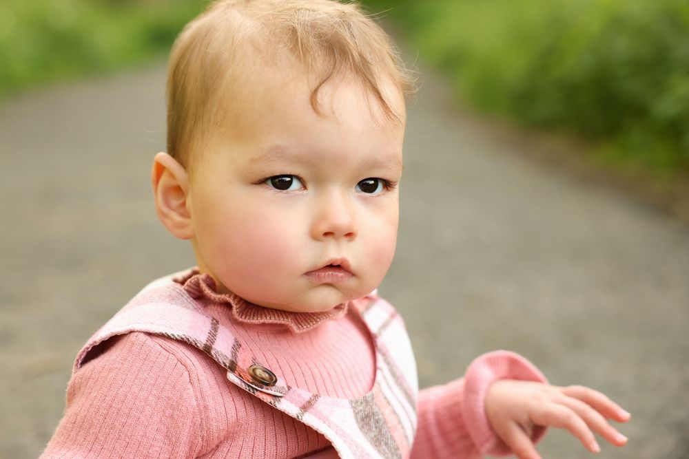 Close up image of baby girl in pink checkered outfit and frilly pink turtleneck posing for photoshoot, outdoor location. western Sydney.