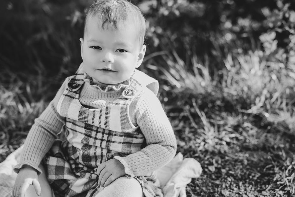 Close up image of baby girl in pink checkered outfit and frilly pink turtleneck posing for photoshoot, outdoor location. western Sydney.
