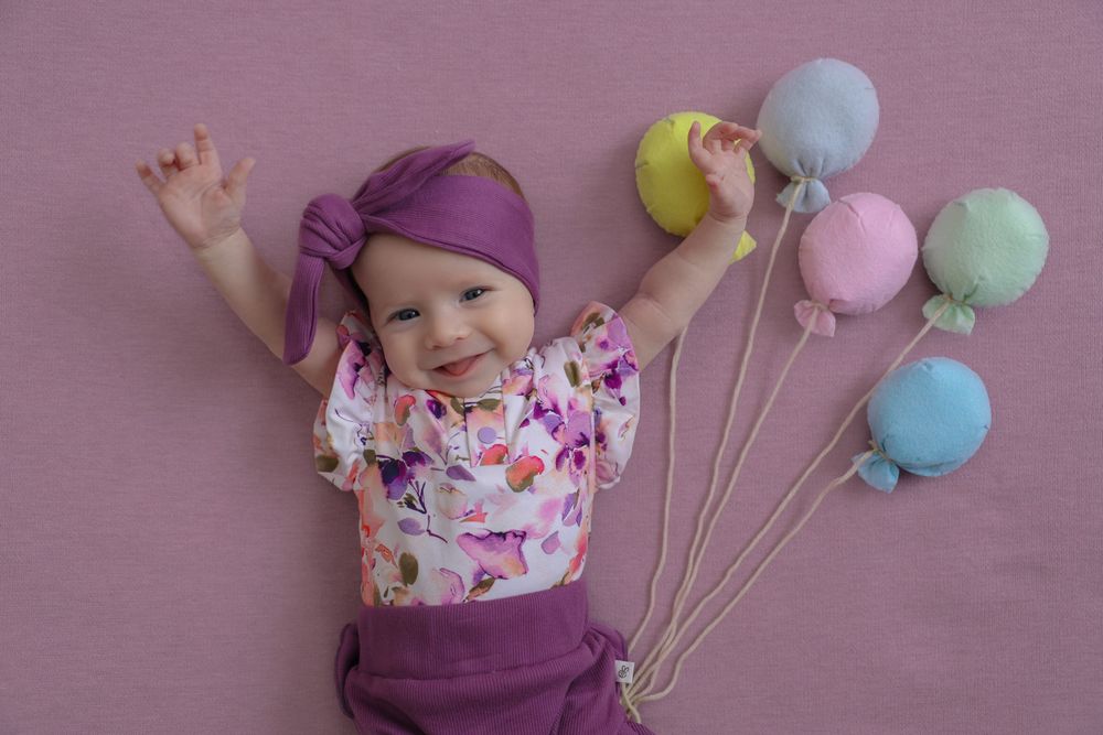 Baby girl during baby mini session, capturing lots of personality in this shot. hot air balloons used for decoration.