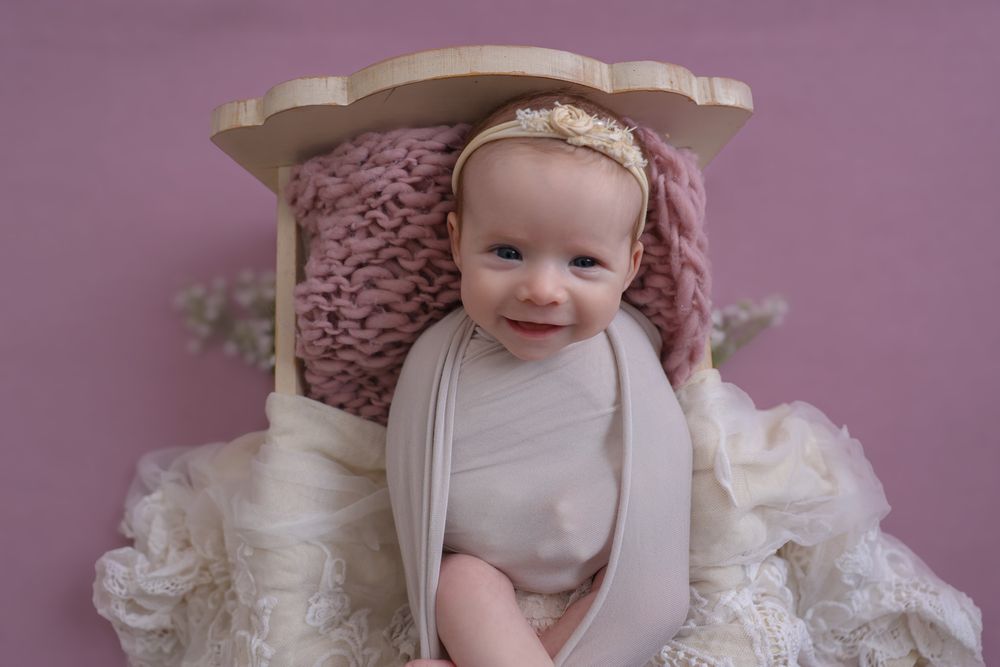 Happy, smiling baby girl during in home photoshoot. wearing large cream bow on her head, cute headband.