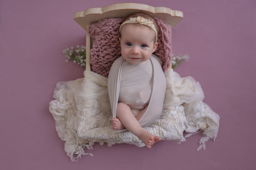Happy, smiling baby girl during in home photoshoot. wearing large cream bow on her head, cute headband.