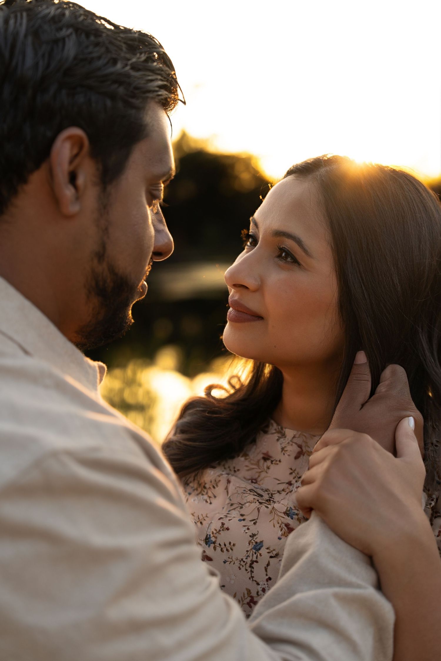 Romantic couple in white clothing sharing an intimate moment during golden hour sunset.