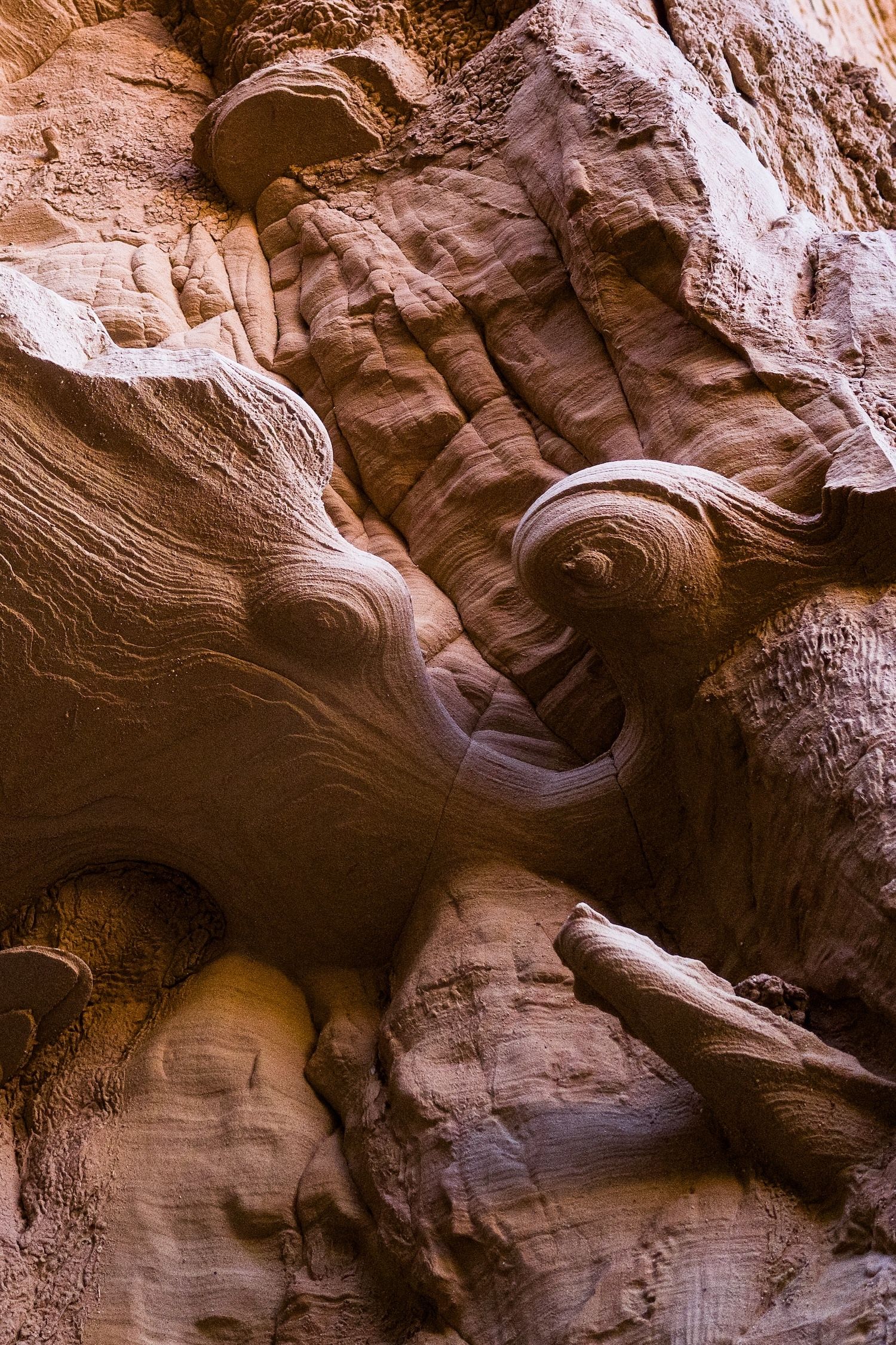 Close-up of swirling red sandstone rock formations with smooth curved erosion patterns in canyon wall.