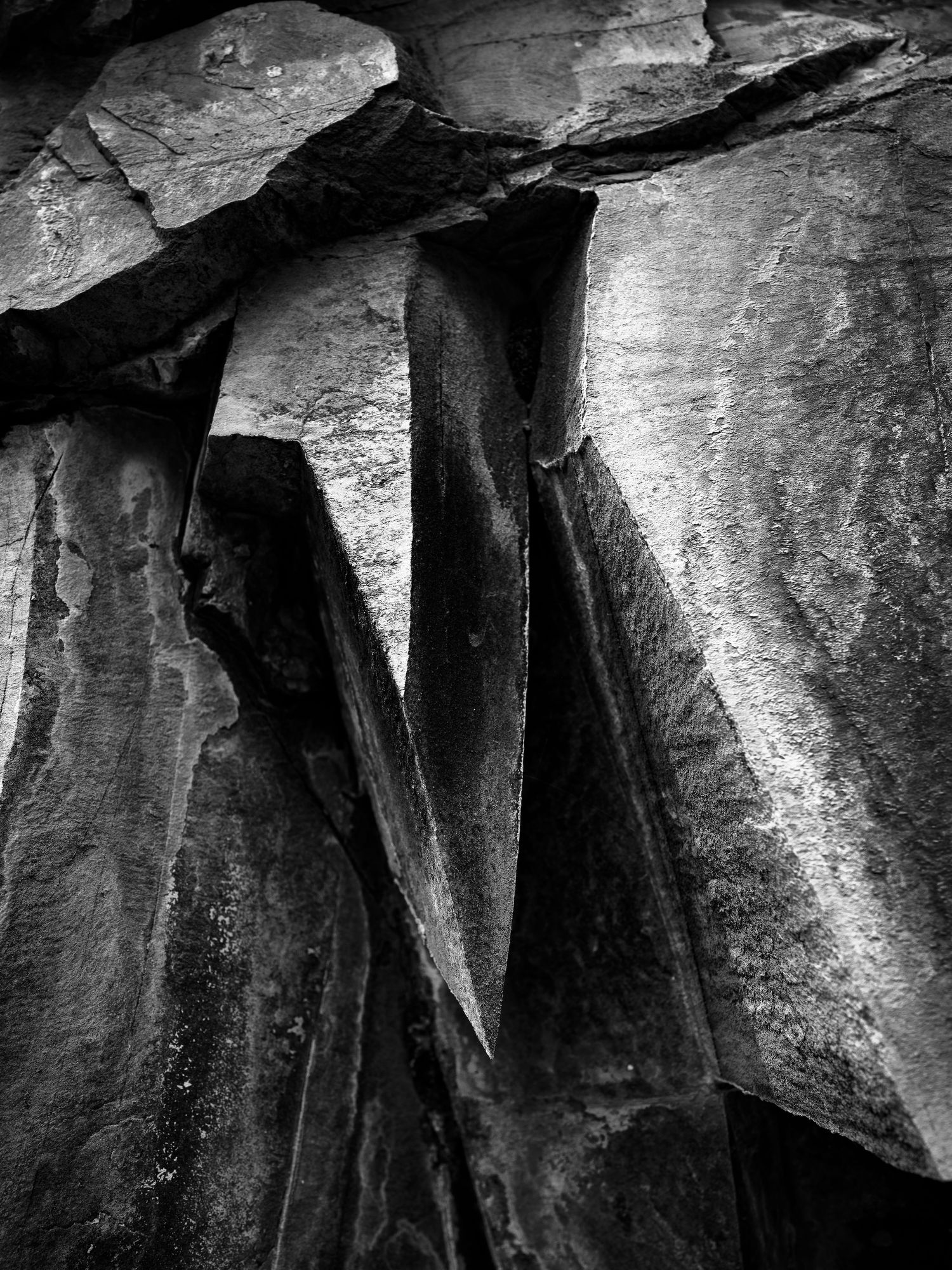 Black-and-white close-up photograph of jagged rock formations, with dramatic shadows and sharp angular edges.