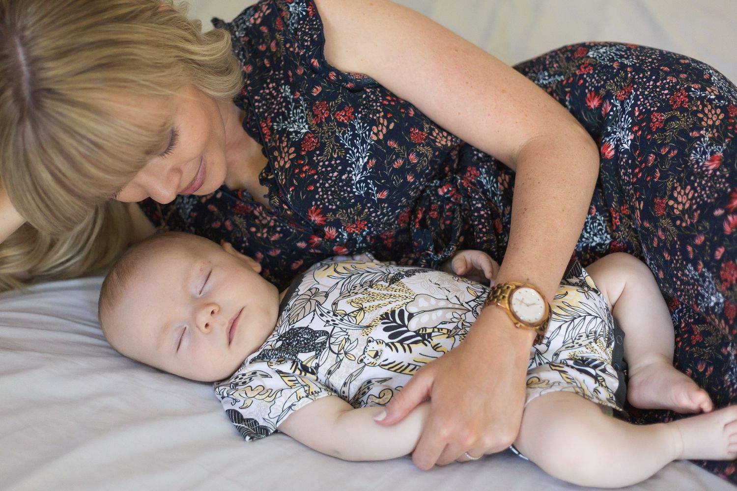 A mother laying on the bed looking at her young baby during an indoor newborn photography session in Perth