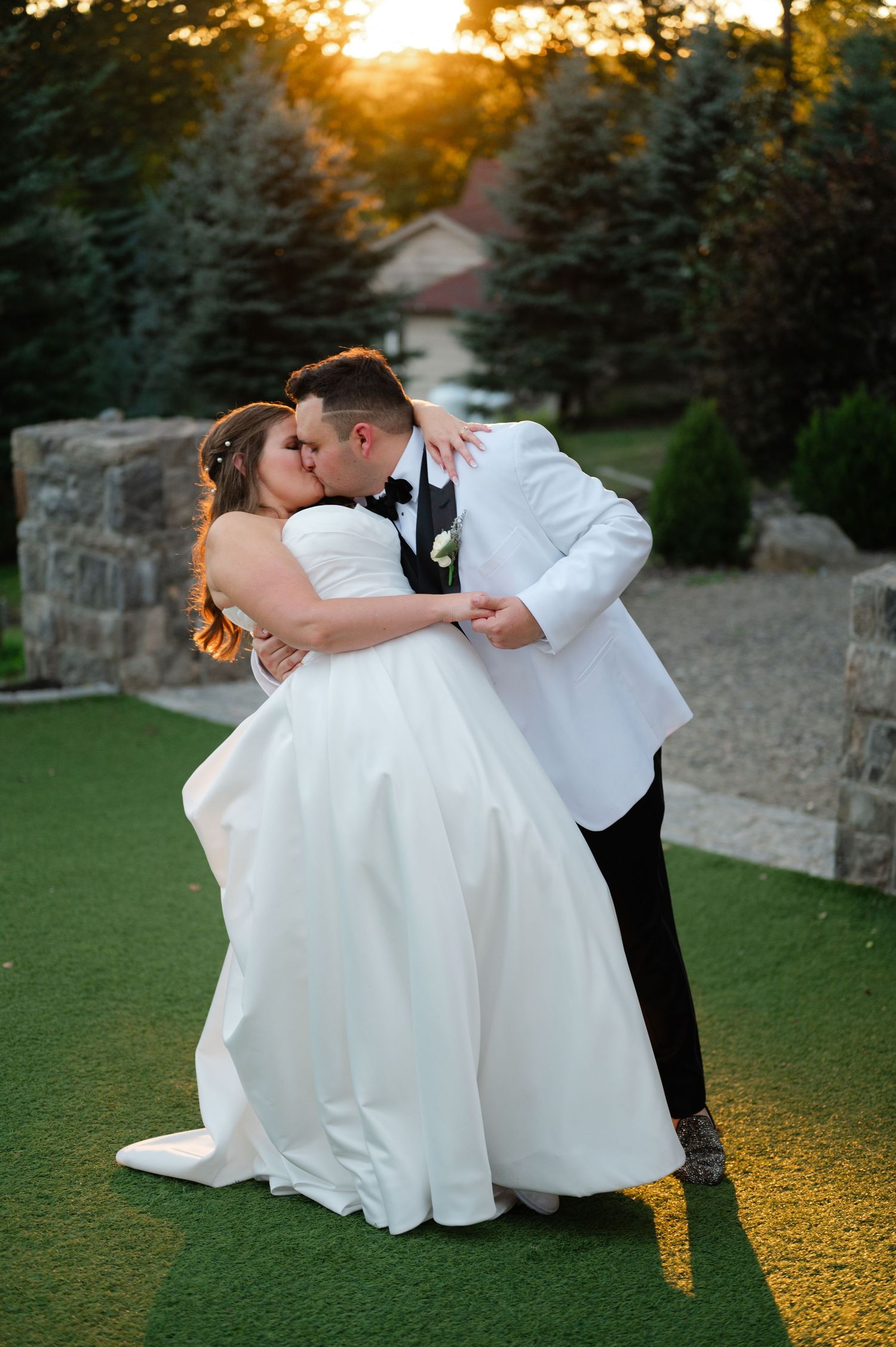 A romantic wedding moment captured as newlyweds share an intimate moment with white floral bouquet against golden backdrop.