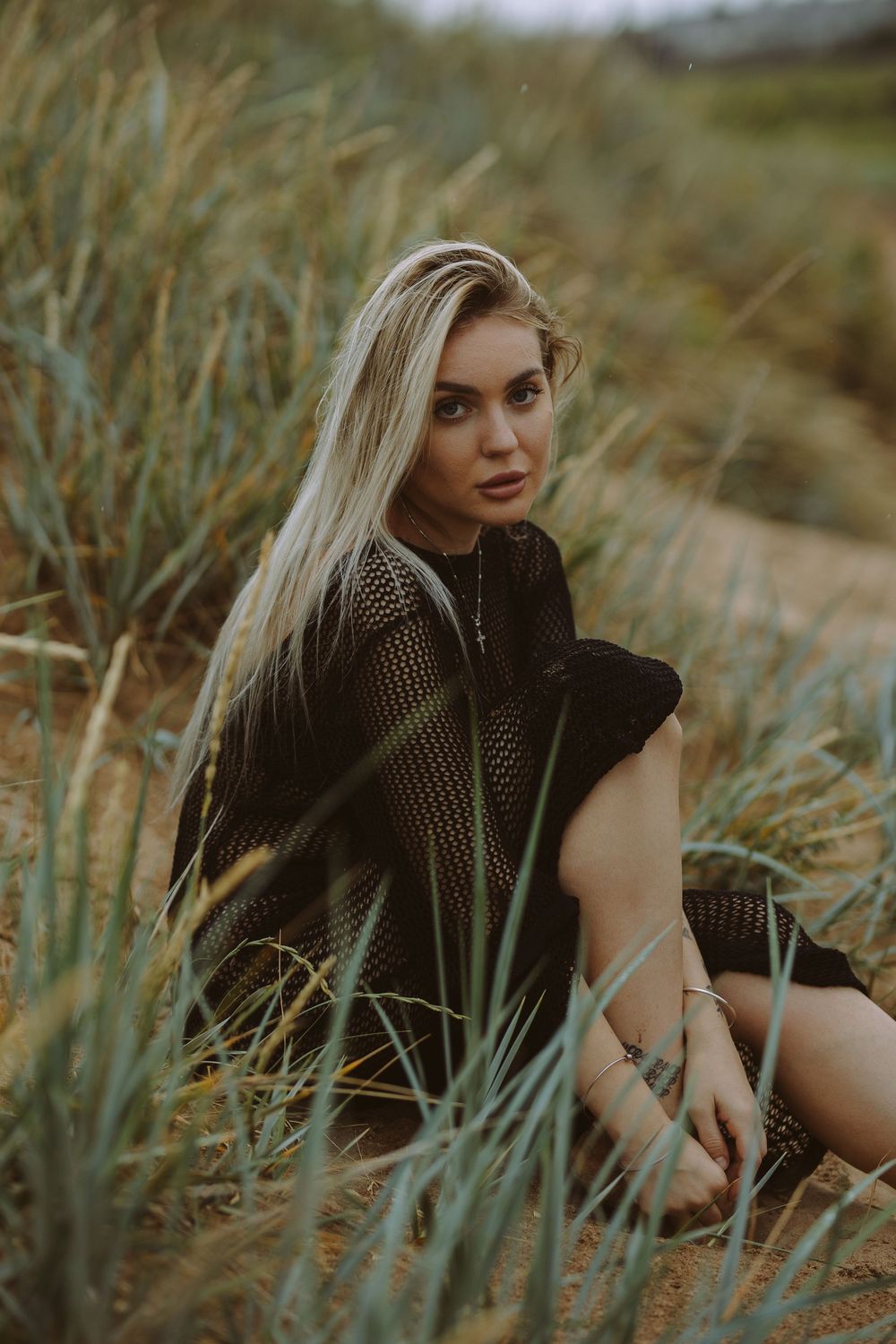 A series of moody outdoor portrait photographs taken in tall grass with natural lighting and earth tones.