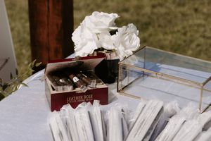 White floral arrangements and paper programs displayed on a table at an outdoor venue.