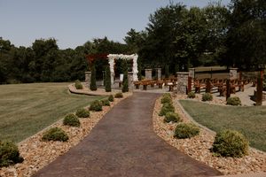 Stone pathway leading to outdoor wedding ceremony setup with wooden benches.