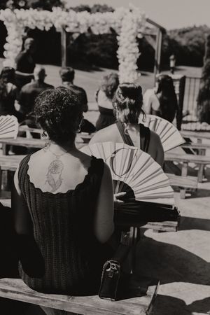 Paper fans arranged in black baskets for outdoor wedding ceremony guests.