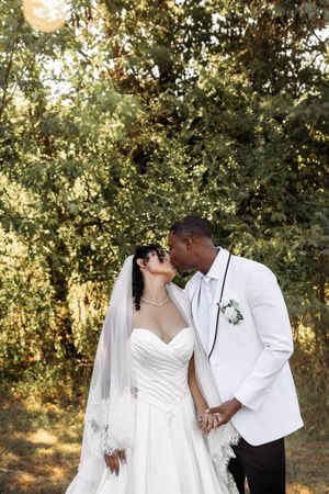 An intimate wedding moment captured between newlyweds against a natural forest backdrop.