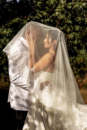 A sunlit wedding portrait showing tender moments between newlyweds under a sheer veil.