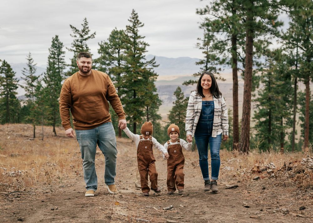 Family walking together on forest trail wearing coordinated casual outfits.