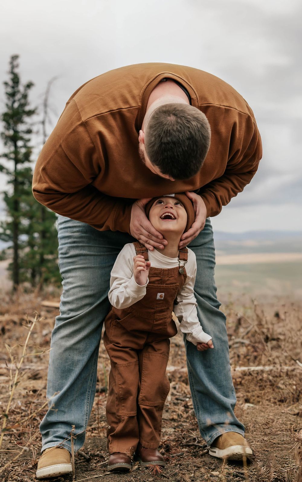 Sequence showing playful interaction between parent and child in brown overalls outdoors.