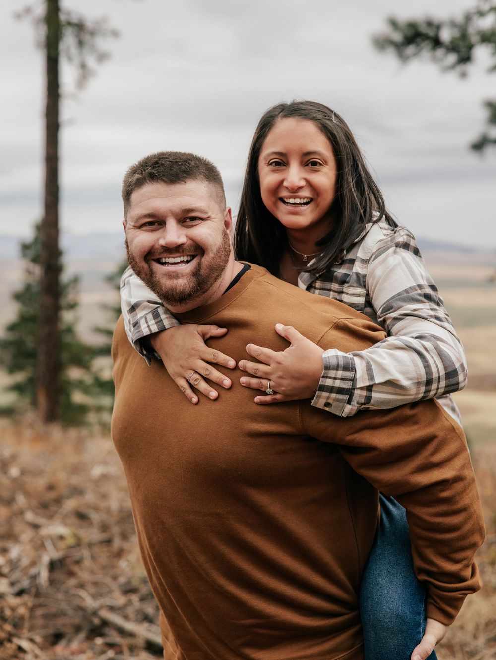 Candid moments of a couple embracing and laughing together on a mountain overlook.