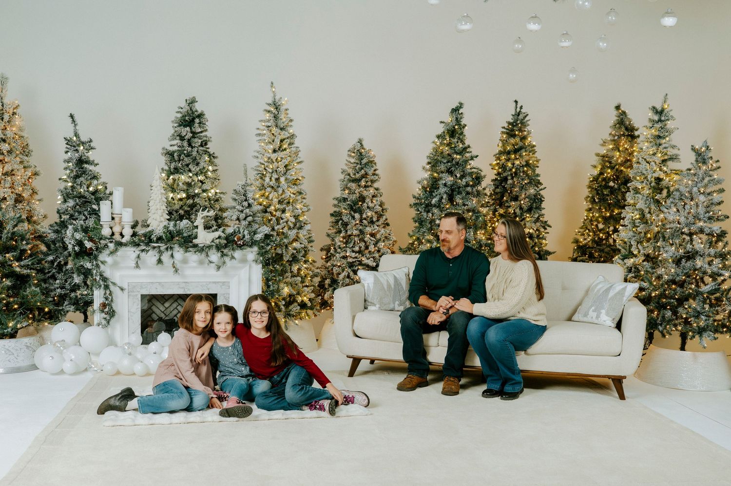 A series of Christmas photos showing people posing in front of decorated trees and holiday decor in a white studio setting.