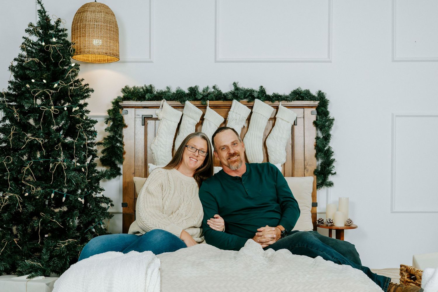 Couple sitting on white couch by decorated Christmas tree sharing romantic moments in holiday setting.