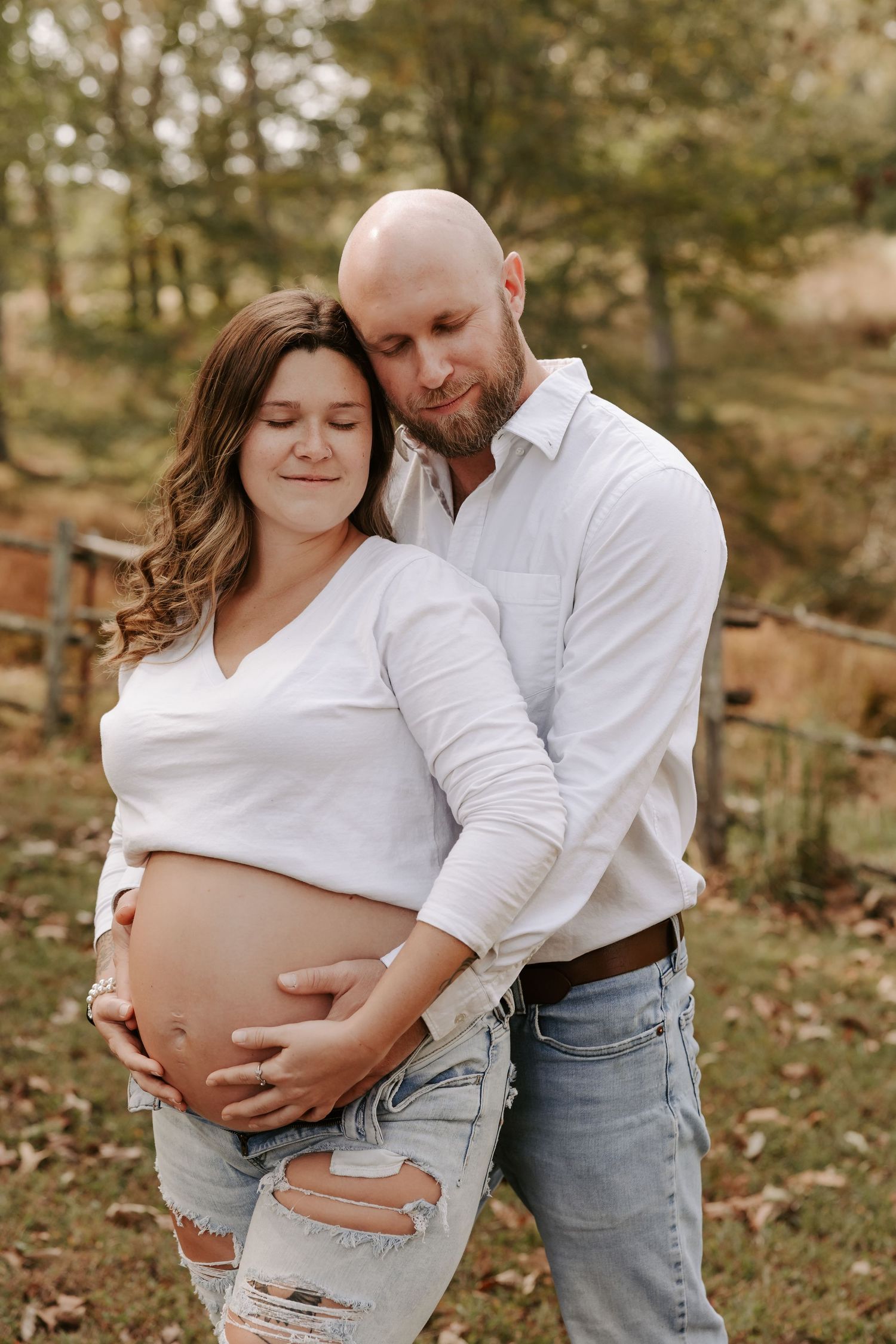 An intimate maternity portrait in a rustic outdoor setting during fall.