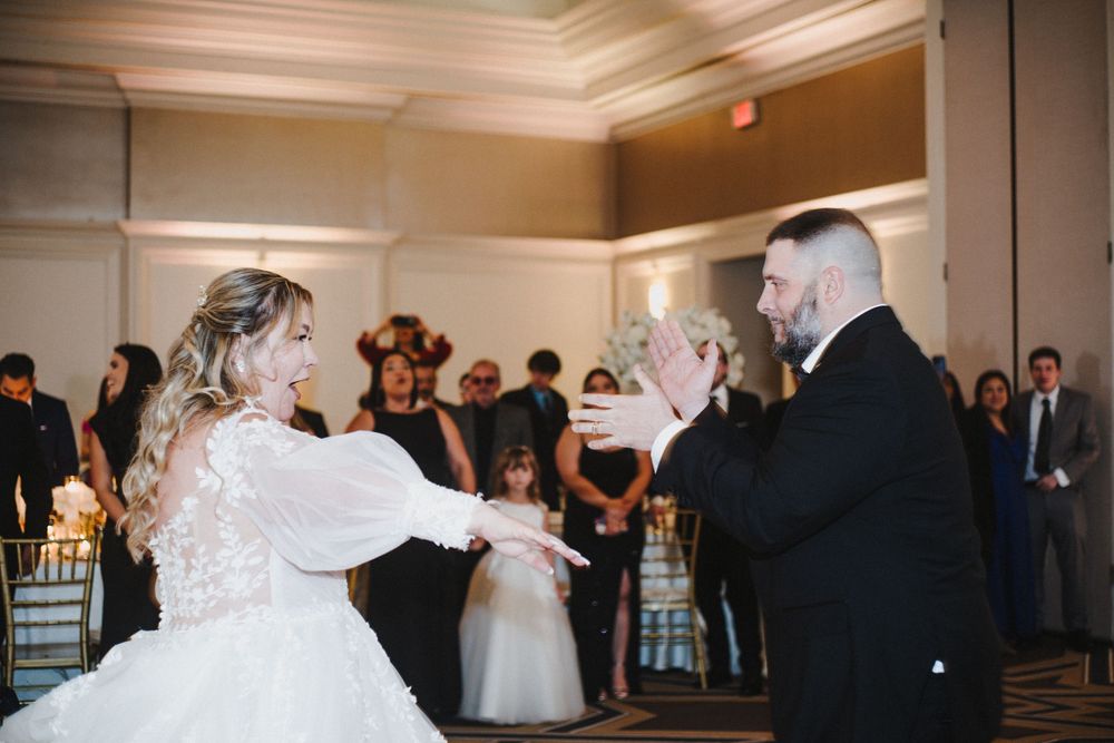 Wedding reception guests dancing and celebrating on a dance floor in an elegant ballroom setting.