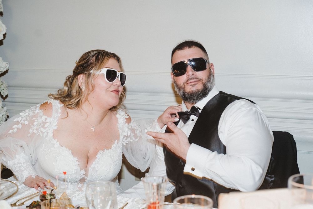 Wedding guests wearing sunglasses and dancing together during a lively reception celebration.