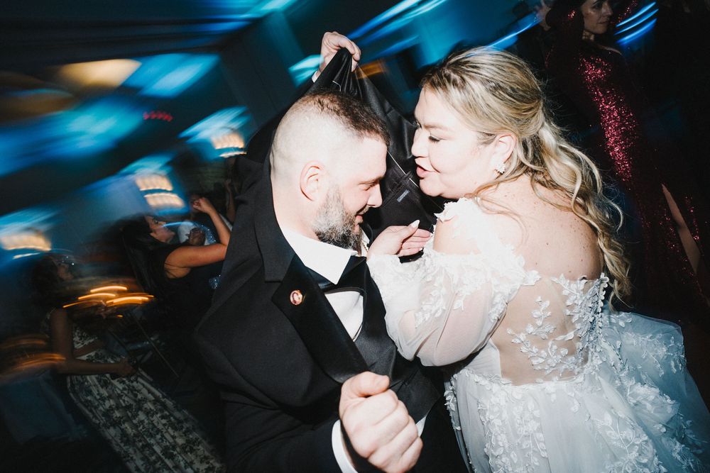 A couple shares romantic moments during their wedding celebration in a dimly lit venue with blue lighting.