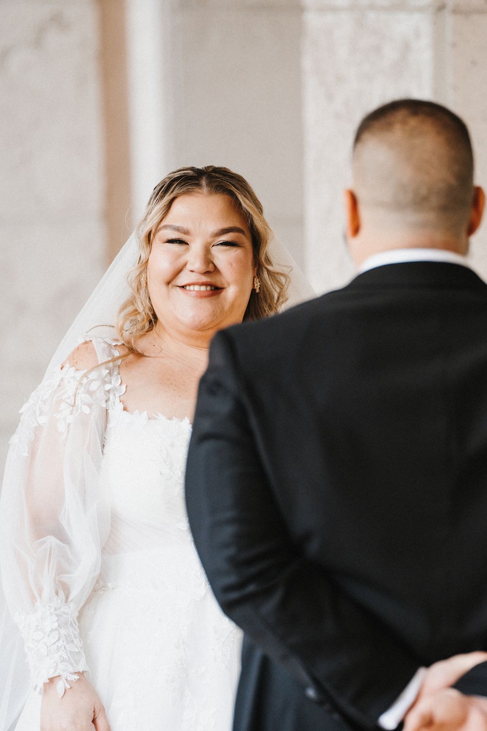 A joyful wedding moment captured showing a bride and groom sharing laughter during their first look.