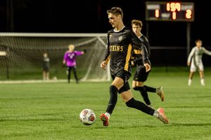 Two soccer players compete for possession of the ball during a night game under bright stadium lights.