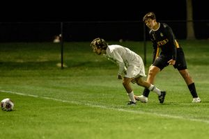 Two soccer players compete for the ball during a nighttime match on an illuminated grass field.