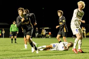 Rugby players compete in a nighttime match on an illuminated field with players tackling and running with the ball.