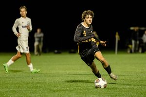 Soccer player in black uniform prepares to kick ball during nighttime match on grass field.