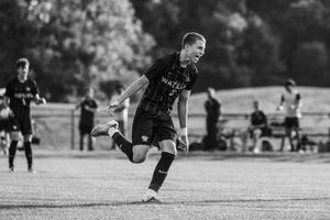 A sequence of black and white soccer action shots showing players kicking and running on a grass field during a match.