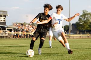 Soccer players battle for possession of the ball during an intense match on a grassy field.