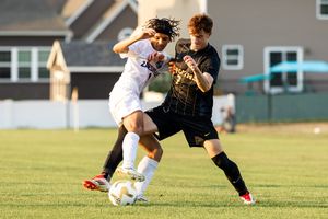 Soccer players compete for the ball during an intense match on a grass field.