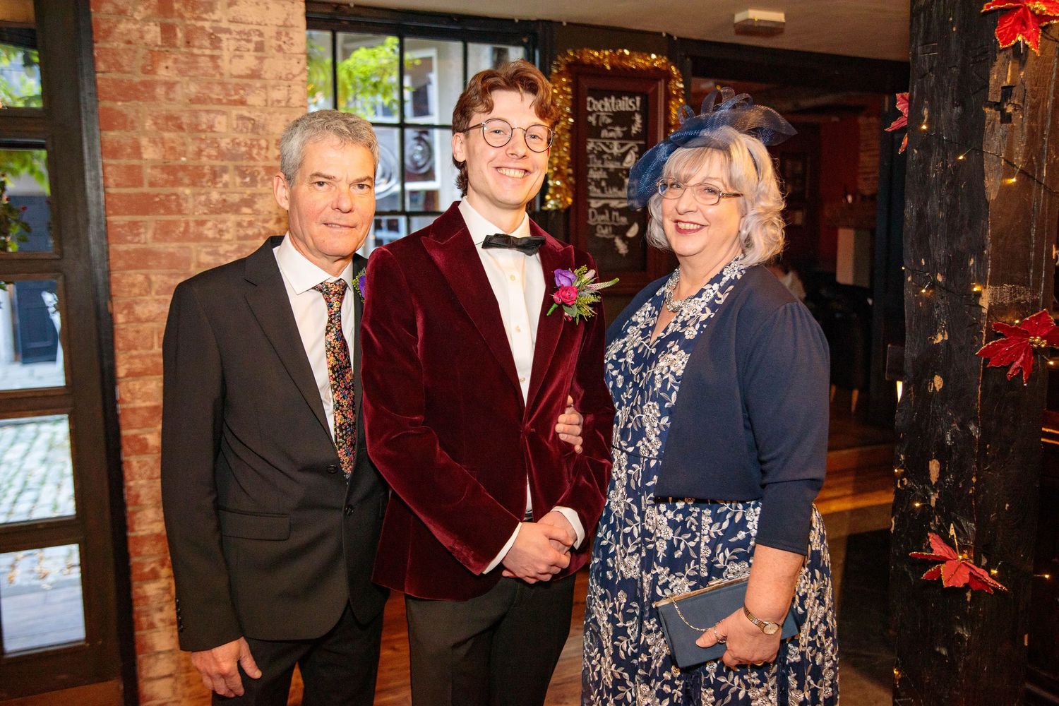 Wedding reception guests mingle in brick-walled venue decorated with holiday decor.