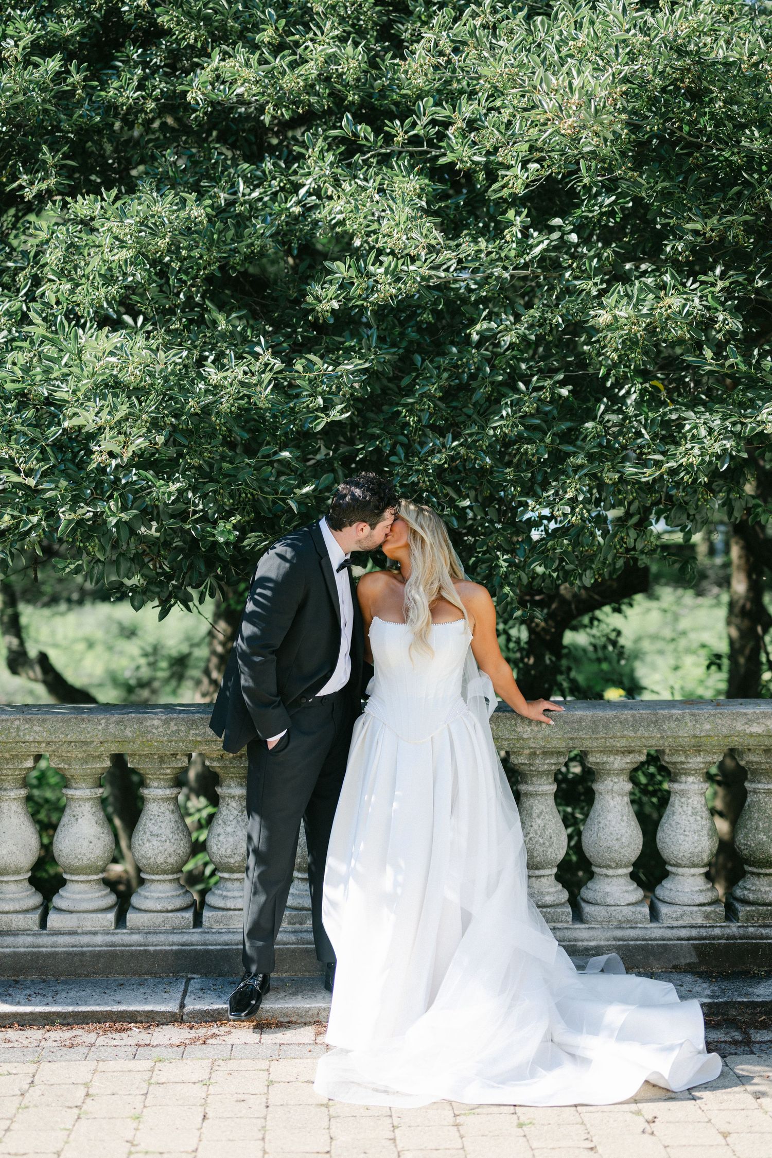 A white wedding dress flows gracefully across green grass in a series of romantic bridal portraits.