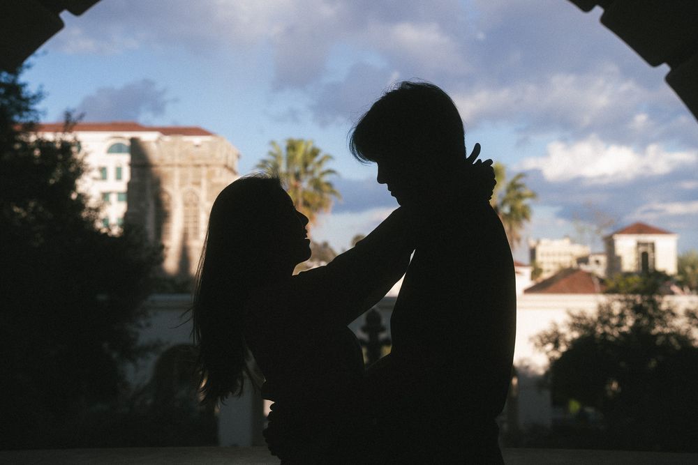 Intimate silhouette of couple leaning close with city architecture in the background.