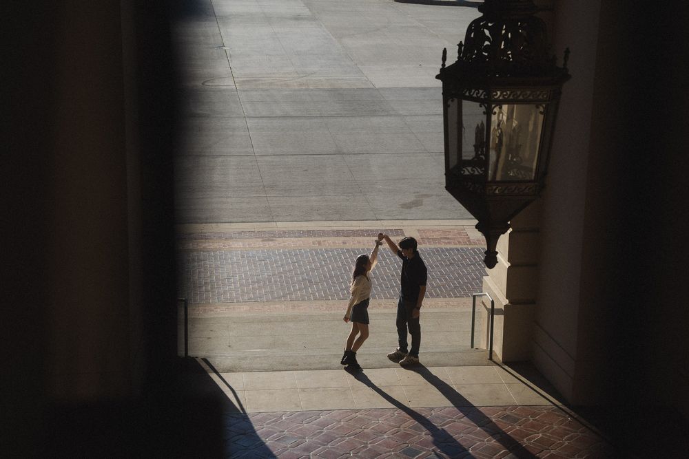 Couple dancing beneath the grand arch at Pasadena City Hall during golden hour.