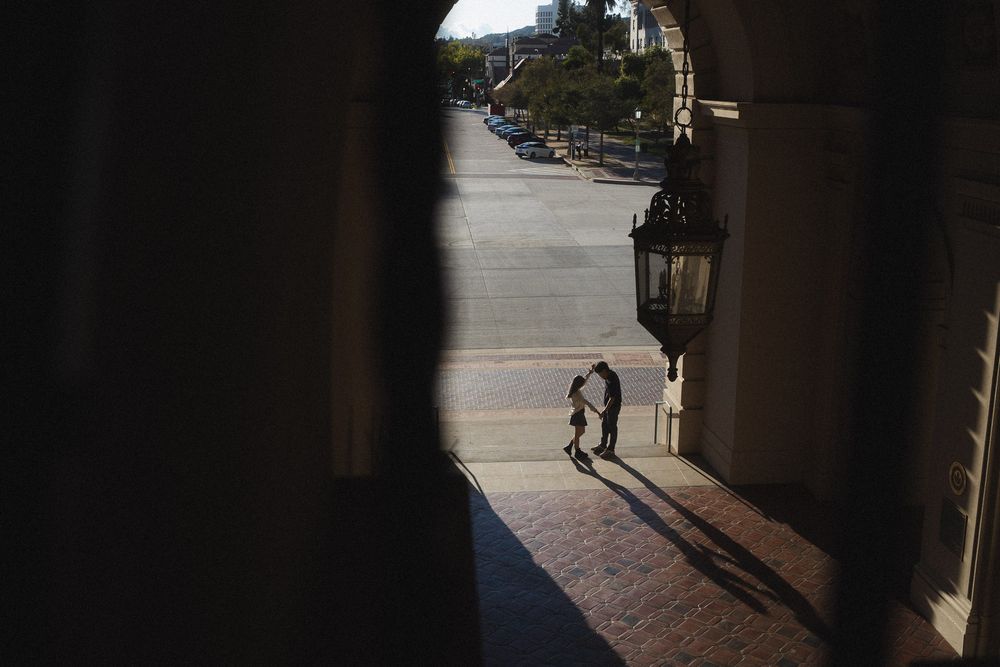 Couple walking through open courtyard with long shadows in Pasadena City Hall.