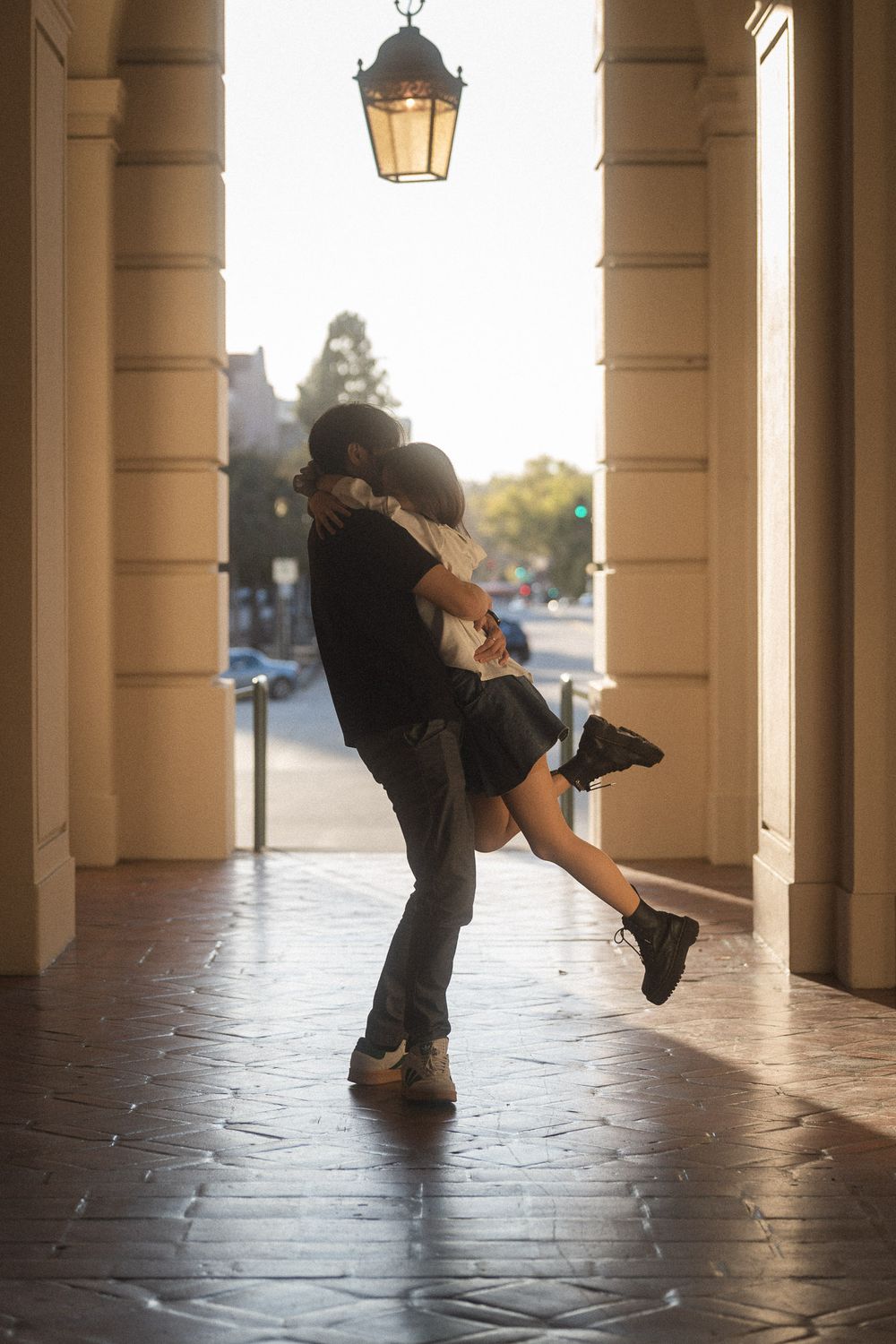 Couple embracing warmly in the golden light at Pasadena City Hall courtyard.