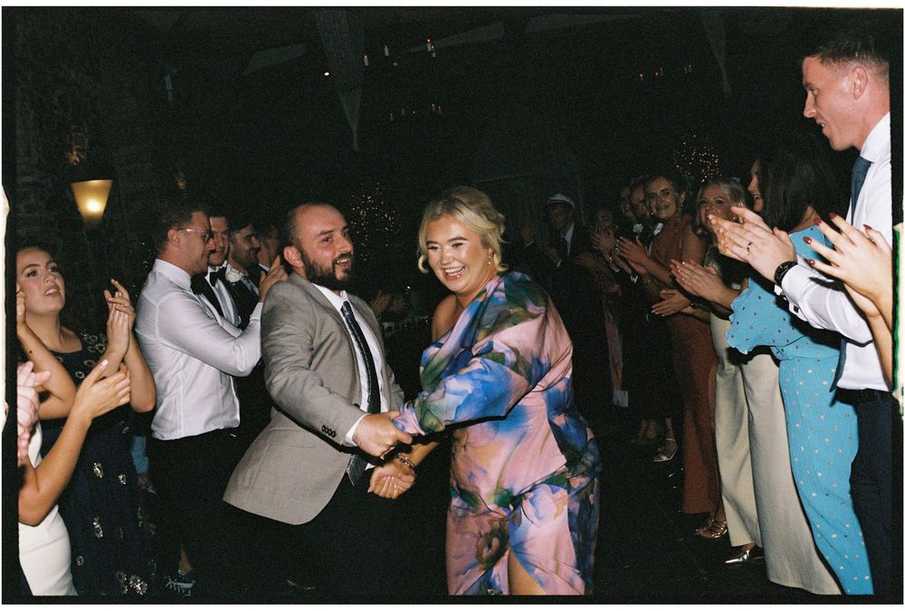Wedding guests dancing and celebrating on a dark dance floor.