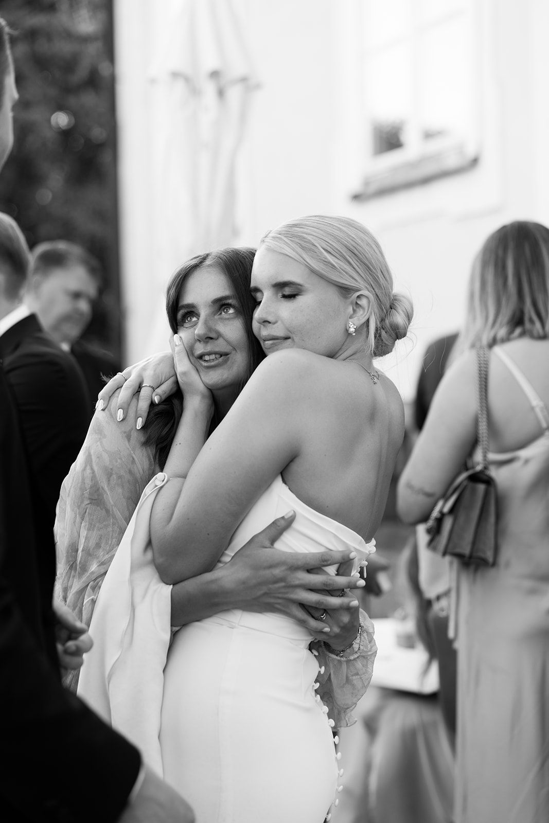 A series of black and white wedding photos showing emotional embraces and reactions during a special moment.