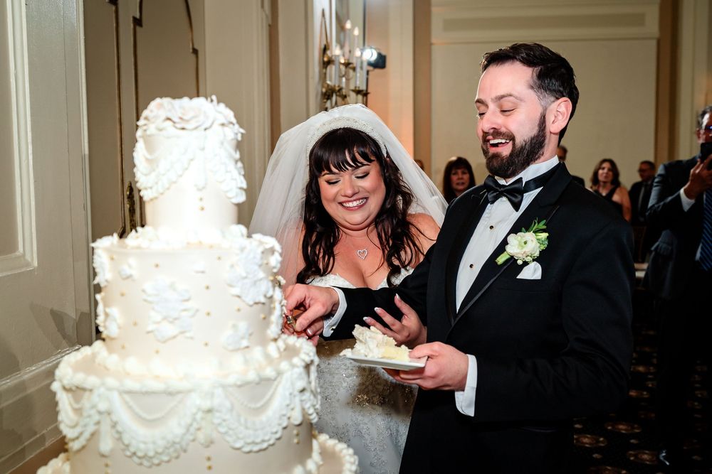 Elegant white wedding cake being served to guests at reception.